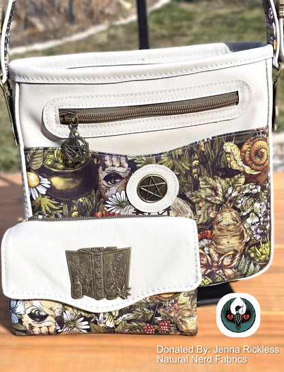 Cream leather handbag and wallet with nature-themed pattern and bronze hardware on a wooden surface