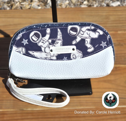 white and navy wallet wristlet with an astronaut design on a wooden surface
