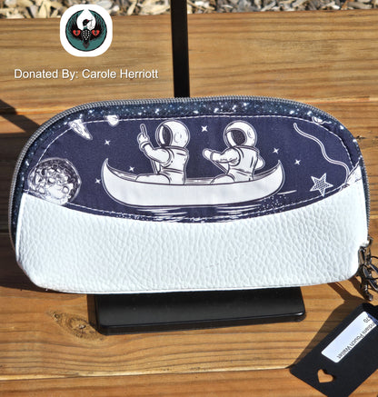 white and navy wallet wristlet with an astronaut design on a wooden surface