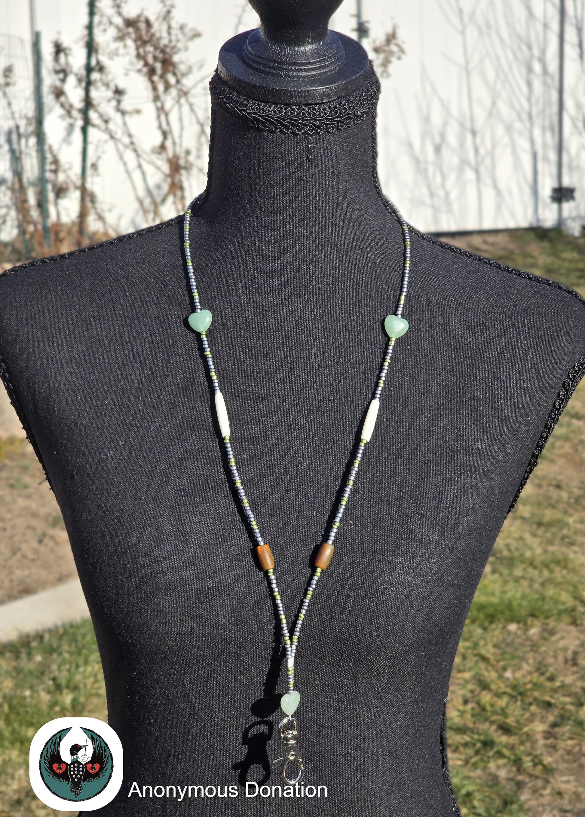 Beaded lanyard with green and brown beads on a mannequin against an outdoor background