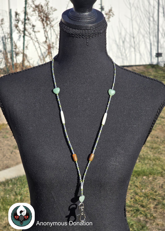 Beaded lanyard with green and brown beads on a mannequin against an outdoor background