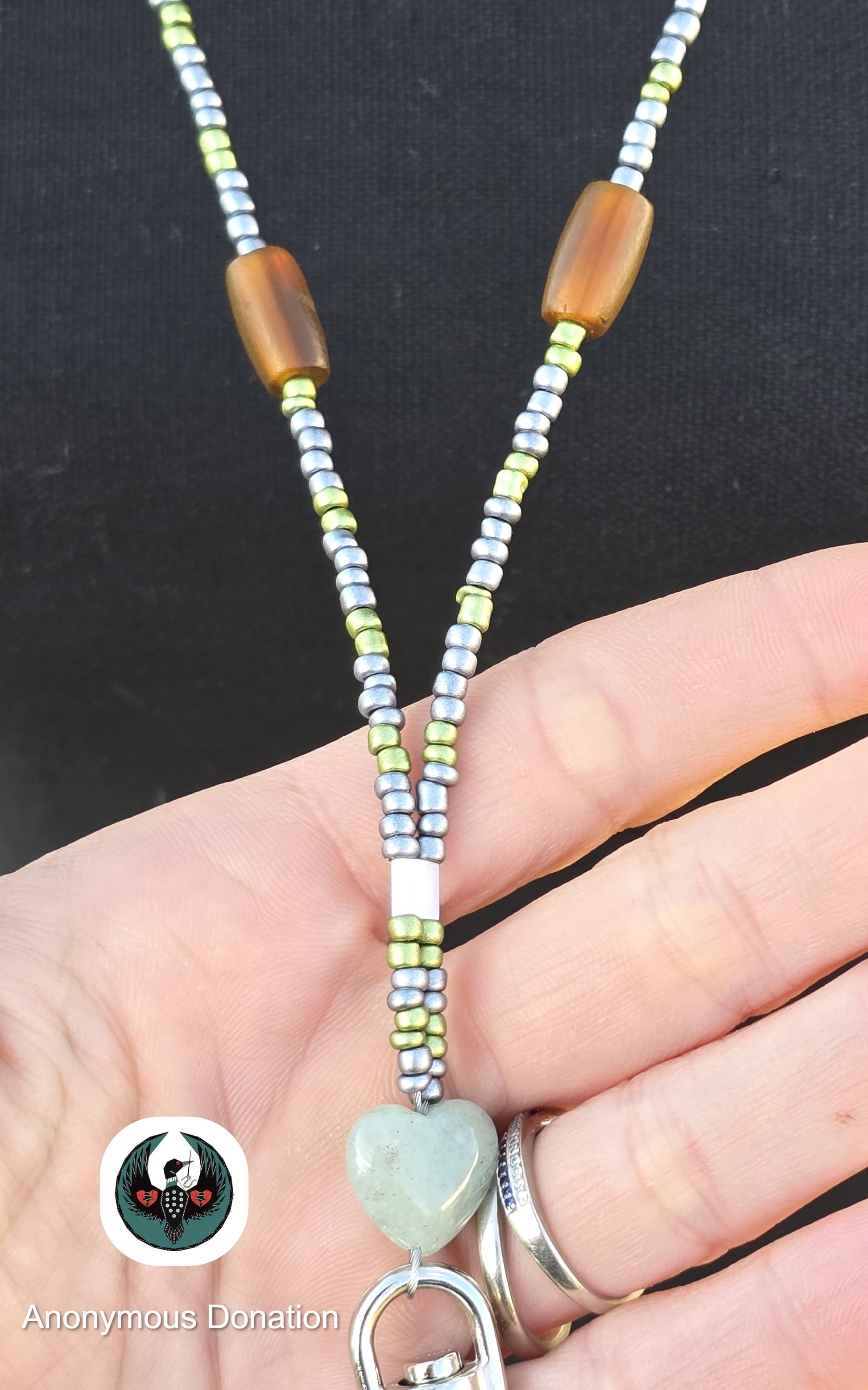 close up of a beaded lanyard with green and brown beads and jade colors heart accents on a mannequin 