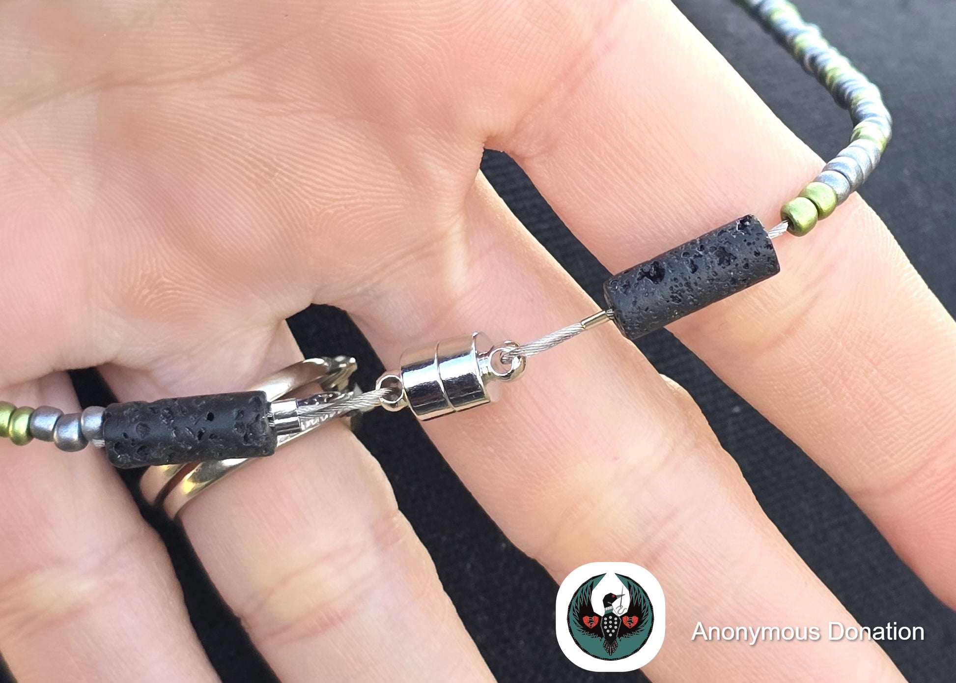 close up of a magnetic clasp flanked on either side by black lava bead tubes