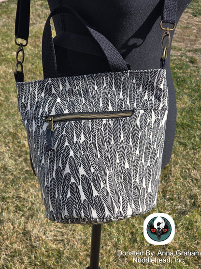Black and white patterned bag on a mannequin with a grassy background