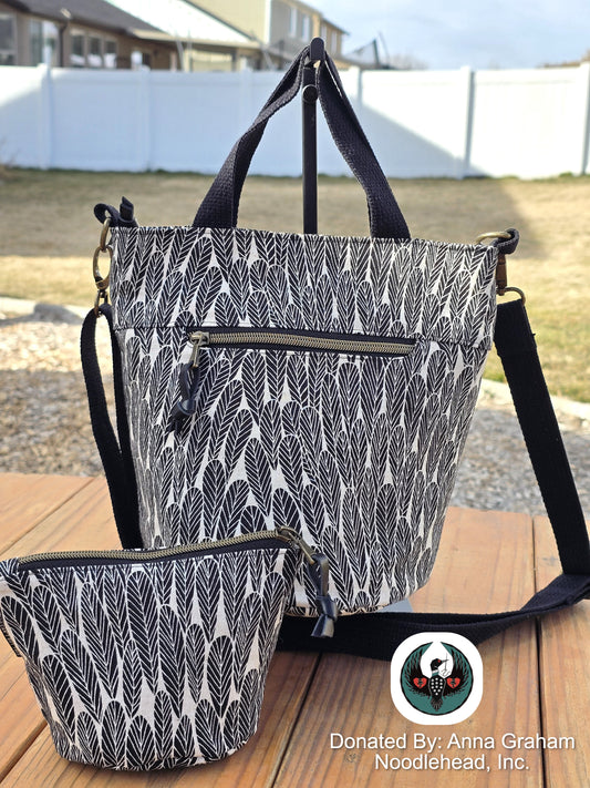 Black and white patterned tote bag with matching pouch on a wooden surface outdoors.