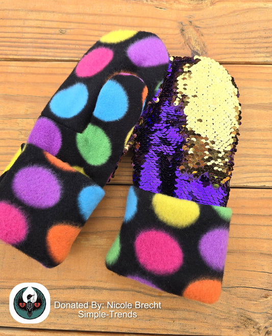 Colorful polka dot mittens with a sequin top on a wooden surface, donated by Nicole Brecht.