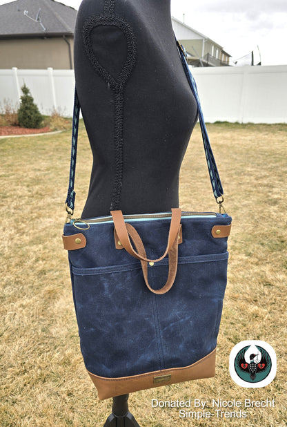 Blue handbag with brown accents on a mannequin outdoors.