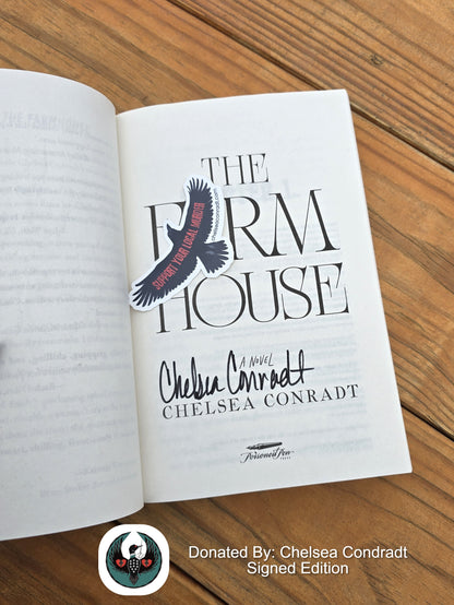 Open book titled 'The Farmhouse' by Chelsea Conradt on a wooden surface. Title page is signed by the author.