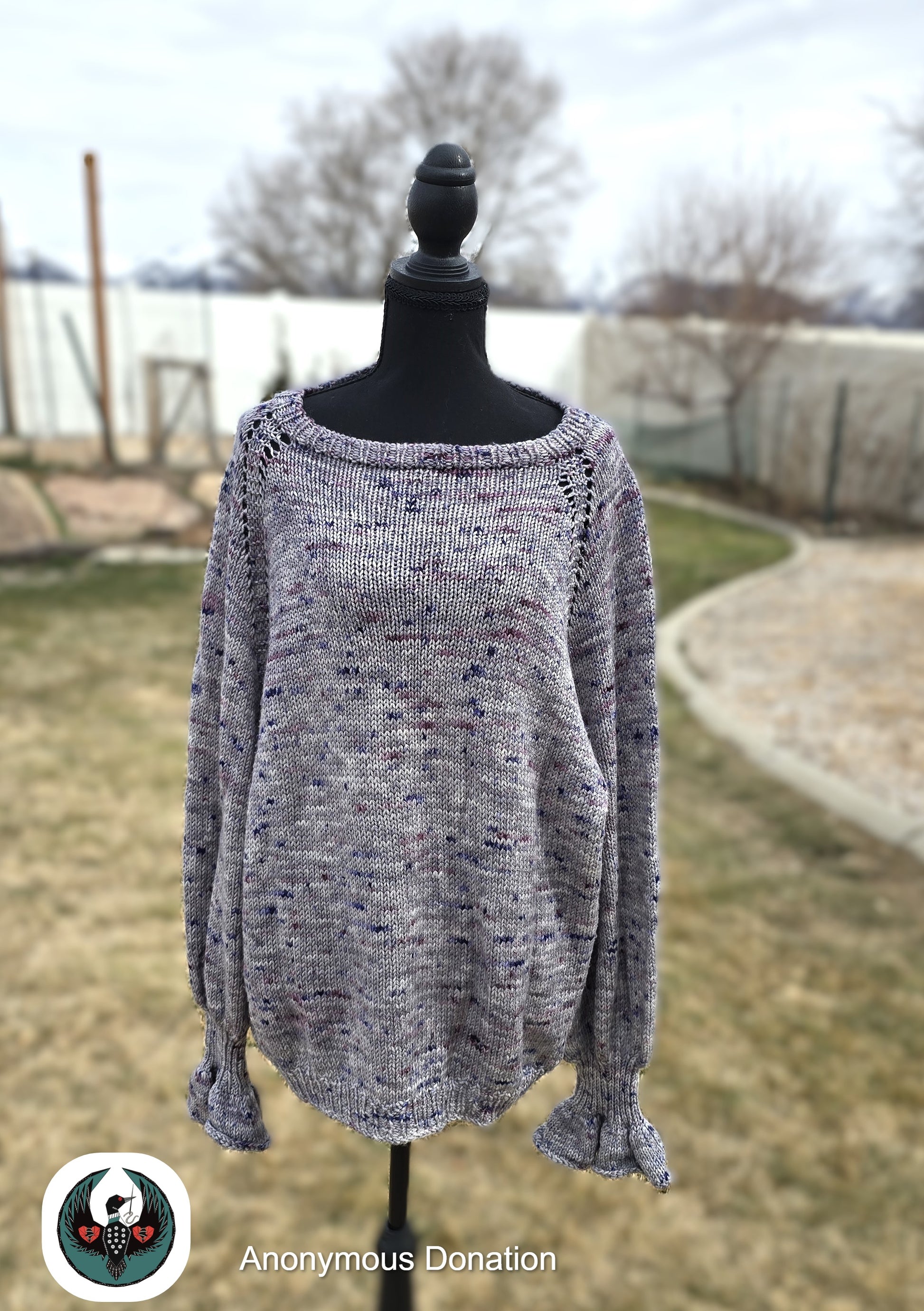 Gray knitted sweater on a mannequin outdoors with a blurred background