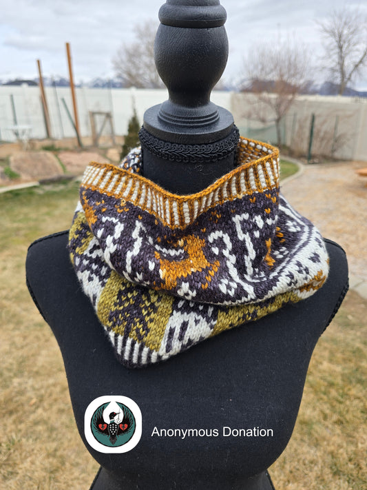 Knitted cowl with geometric pattern on a mannequin against an outdoor background