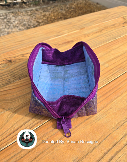 Purple and blue fabric pouch open to act as a storage tray on a wooden surface