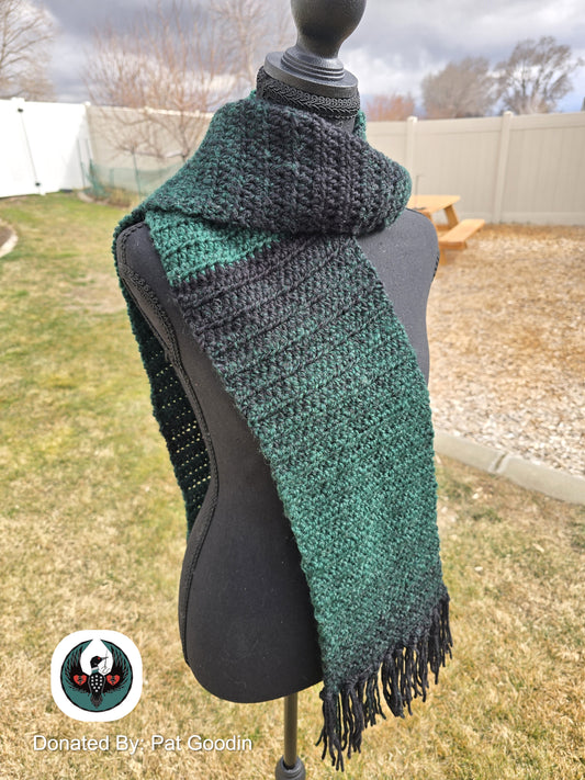 Green and black knitted scarf on a mannequin outdoors.