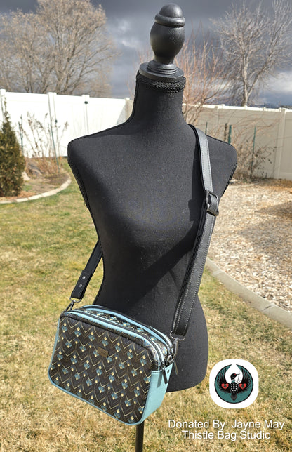 Black and blue patterned handbag on a mannequin outdoors with blurred background