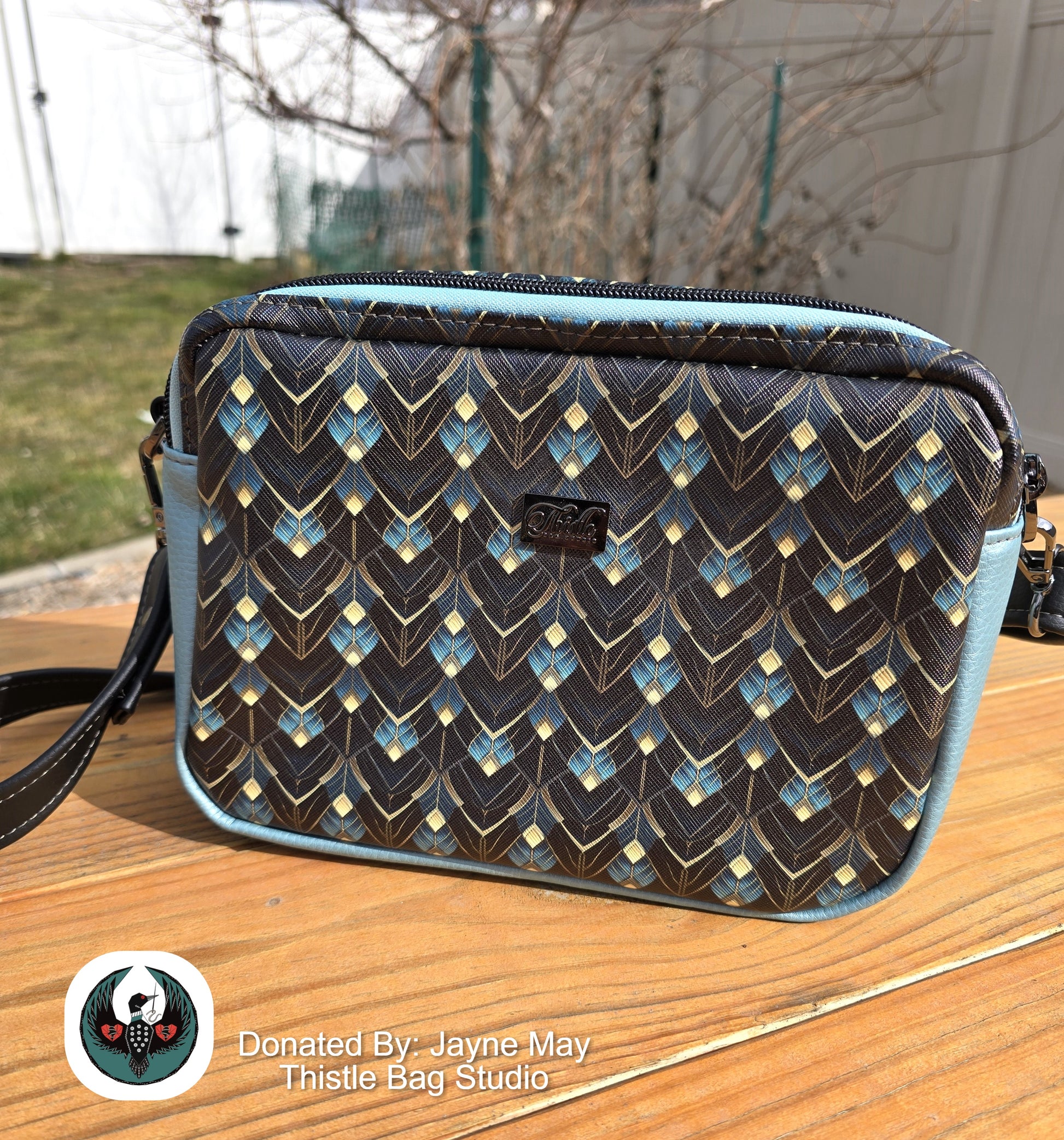 Patterned bag on a wooden surface with a blurred outdoor background