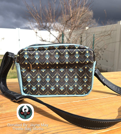 Patterned handbag on a wooden surface with a blurred outdoor background