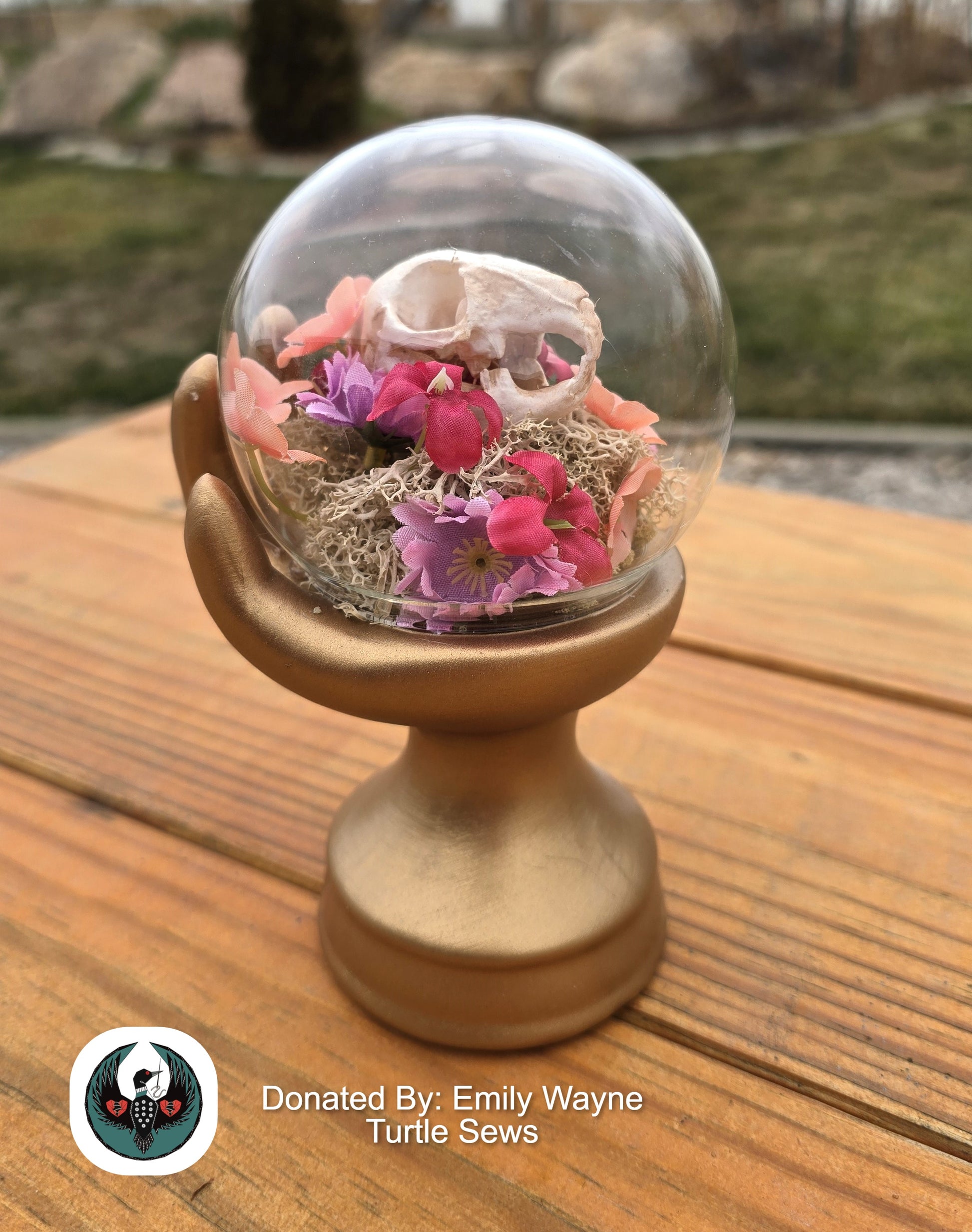 glass orb in a hand sculpture with a resin rabbit skull and silk flowers
