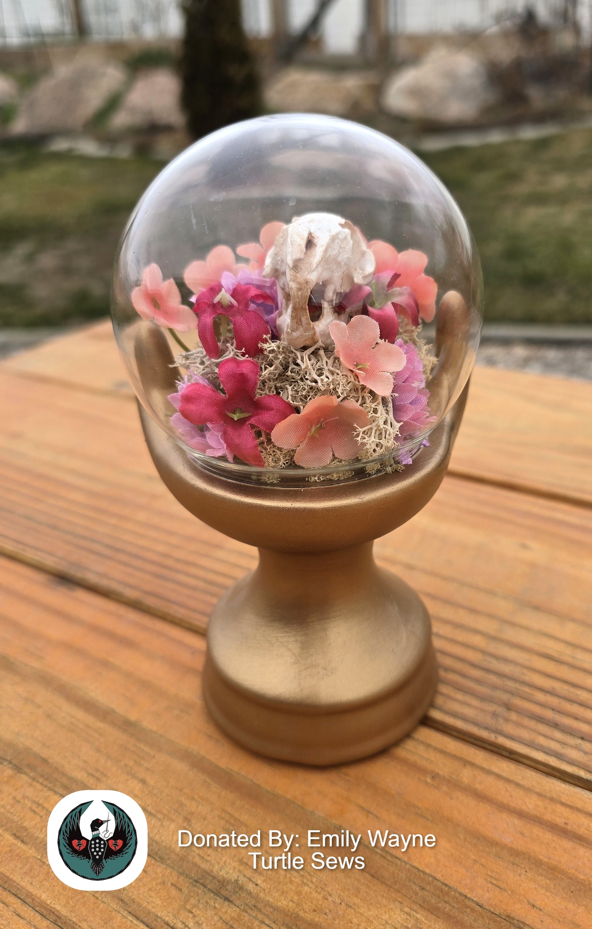 glass orb in a hand sculpture with a resin rabbit skull and silk flowers