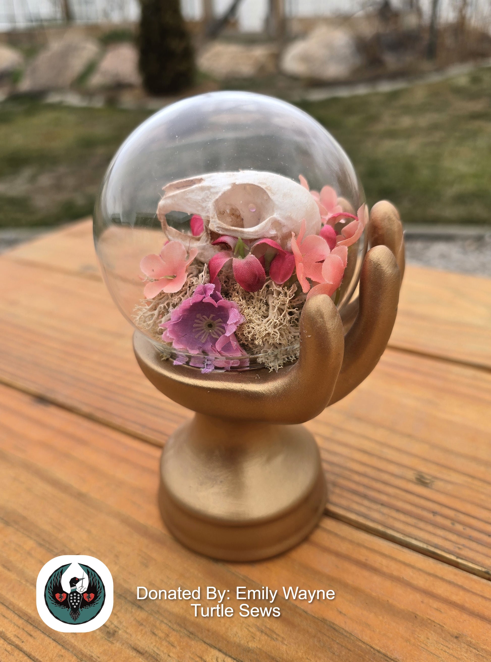glass orb in a hand sculpture with a resin rabbit skull and silk flowers
