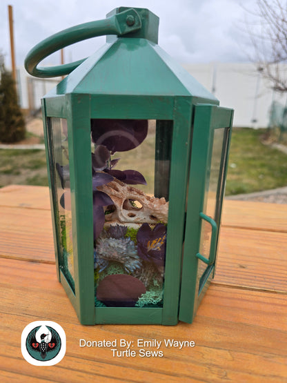 Green lantern with a resin printed chameleon skull and silk flowers inside.