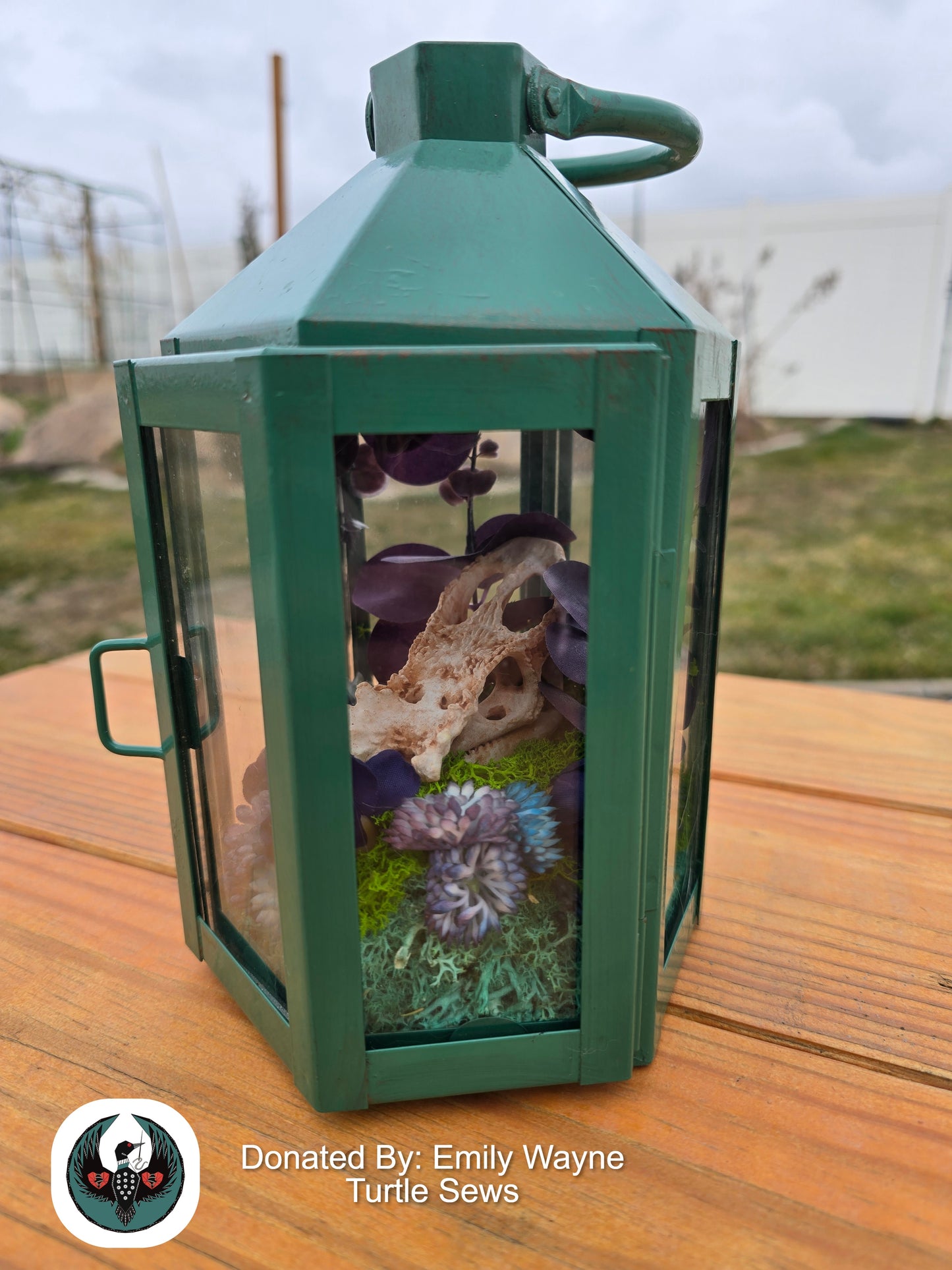Green lantern with a resin printed chameleon skull and silk flowers inside.