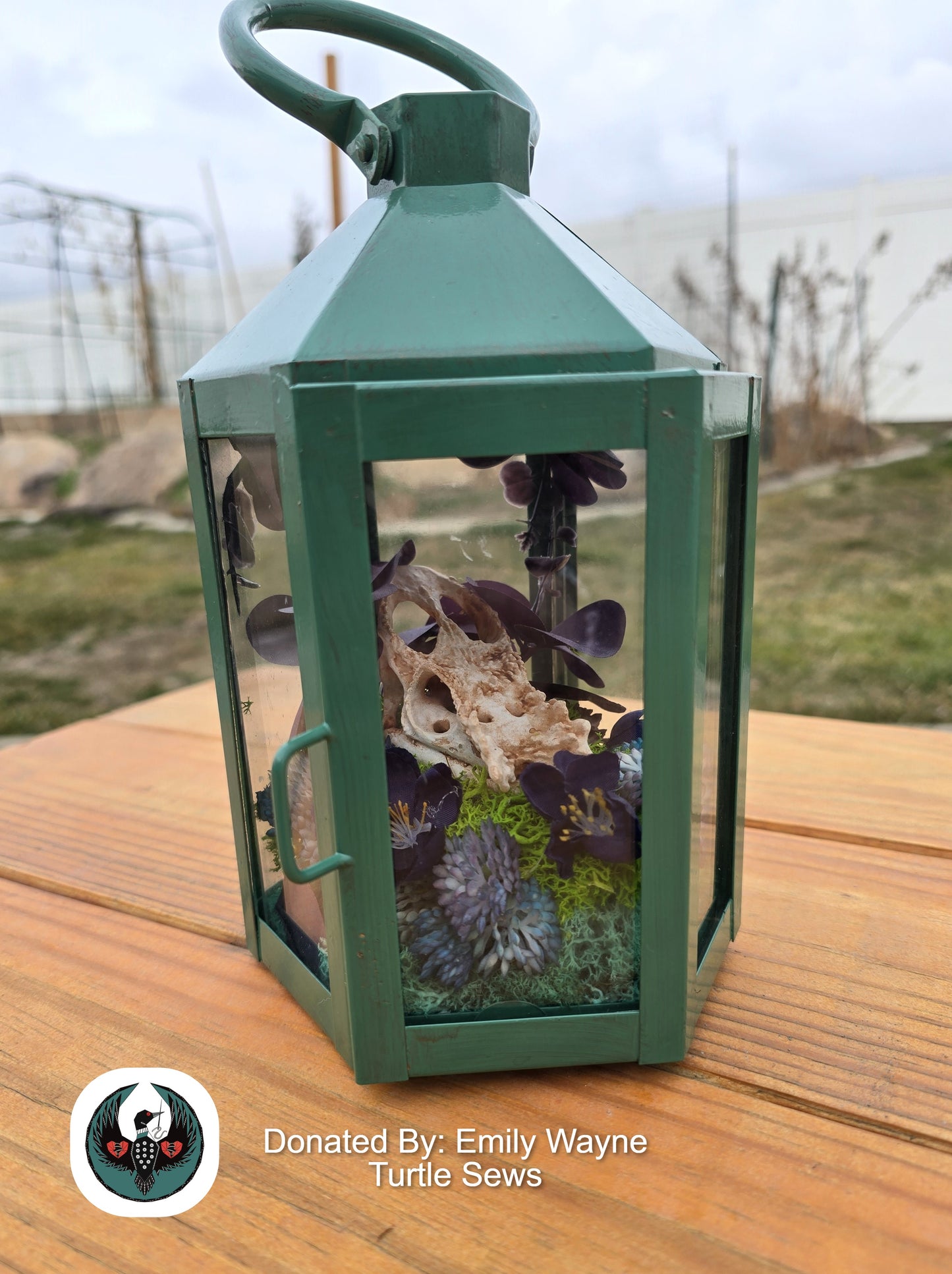 Green lantern with a resin printed chameleon skull and silk flowers inside.
