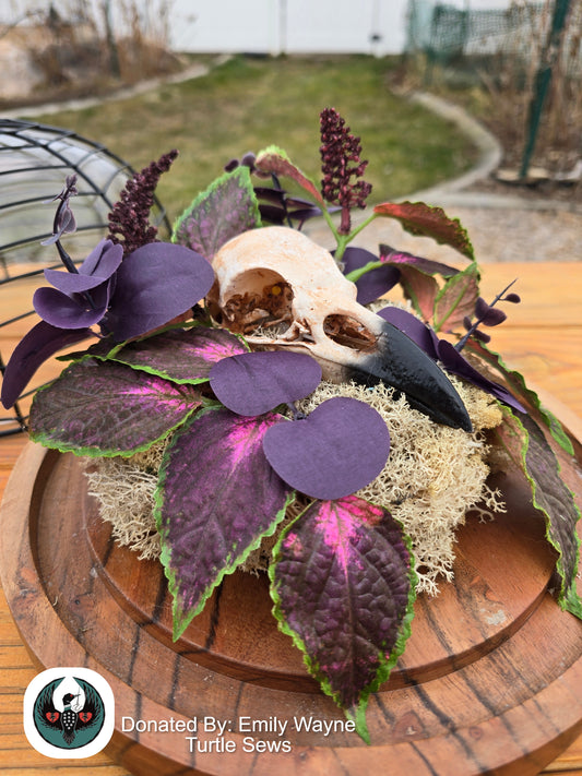 Decorative arrangement with purple leaves and a resin-printed raven skull on a wooden surface, donated by Emily Wayne Turtle Sews.