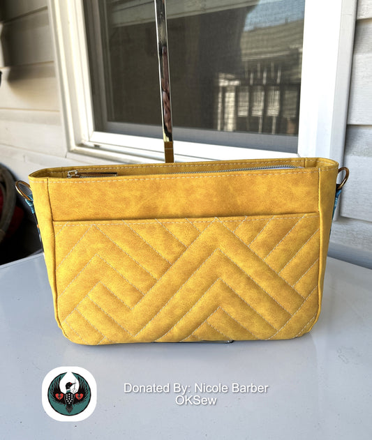 Yellow quilted handbag on a light surface with a blurred background