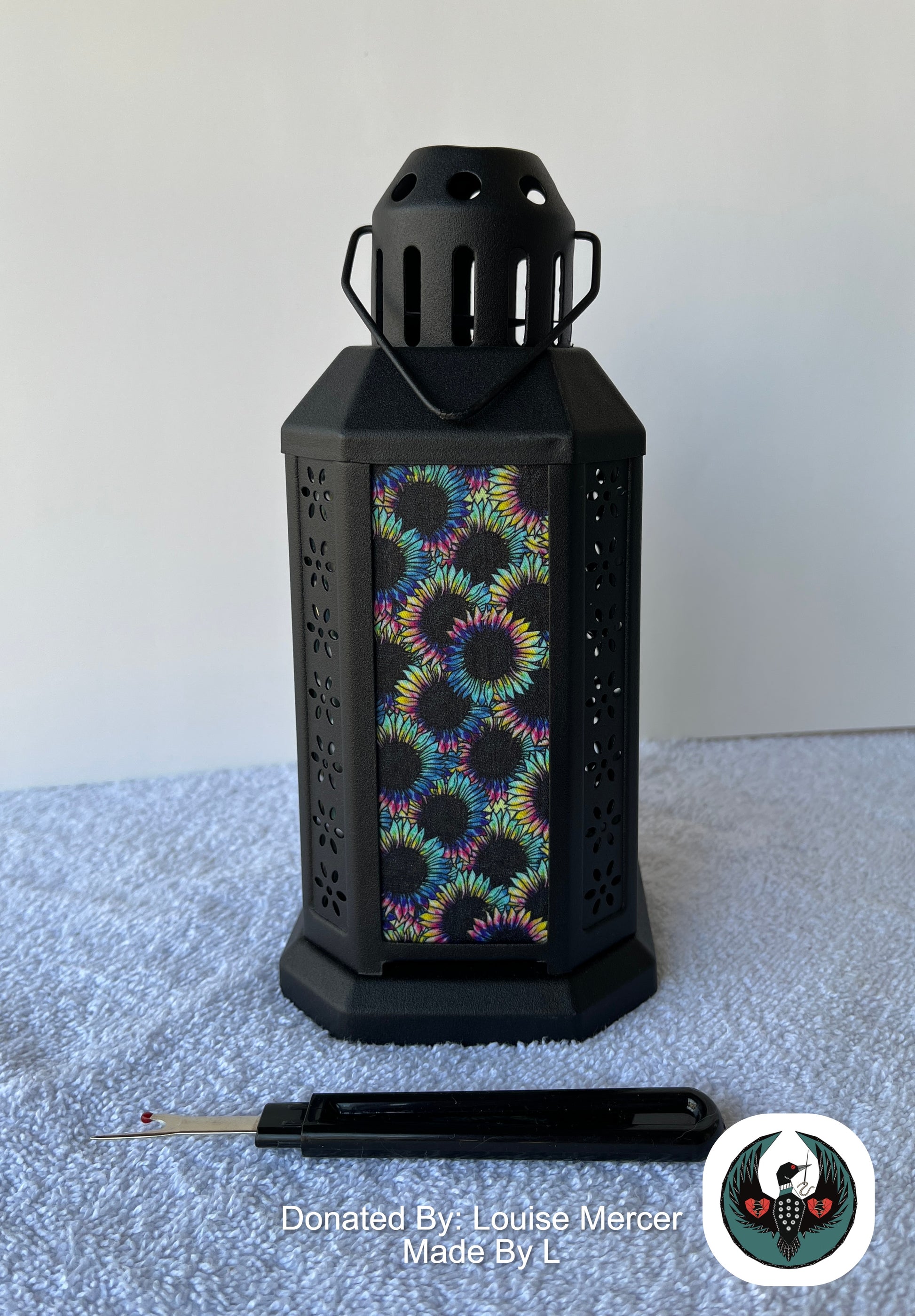 Black lantern with colorful floral pattern on a white surface, donated by Louise Mercer.