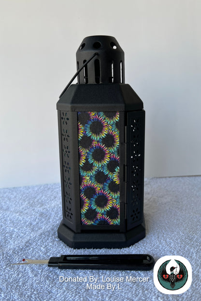 Black lantern with colorful floral pattern on a white surface, donated by Louise Mercer.